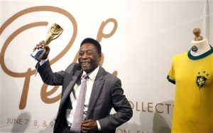 El ex futbolista Pelé levanta su copia del trofeo Jules Rimet Trophy durante una actividad con la prensa para promocionar una subasta de sus artículos deportivos el miércoles, 1 de junio de 2016, en Londres. (AP Photo/Kirsty Wigglesworth)